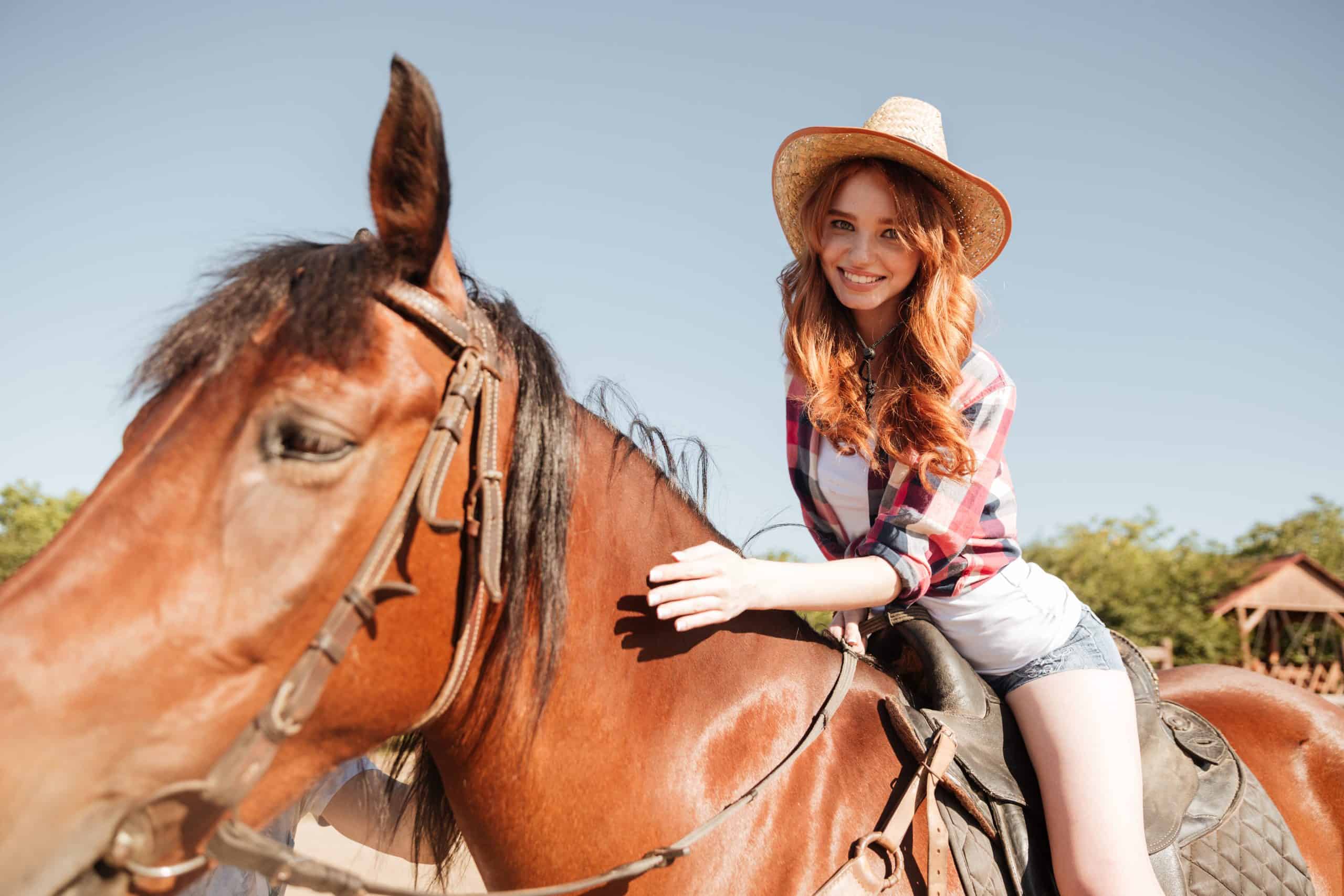 Happy young person cowgirl riding horse on ranch