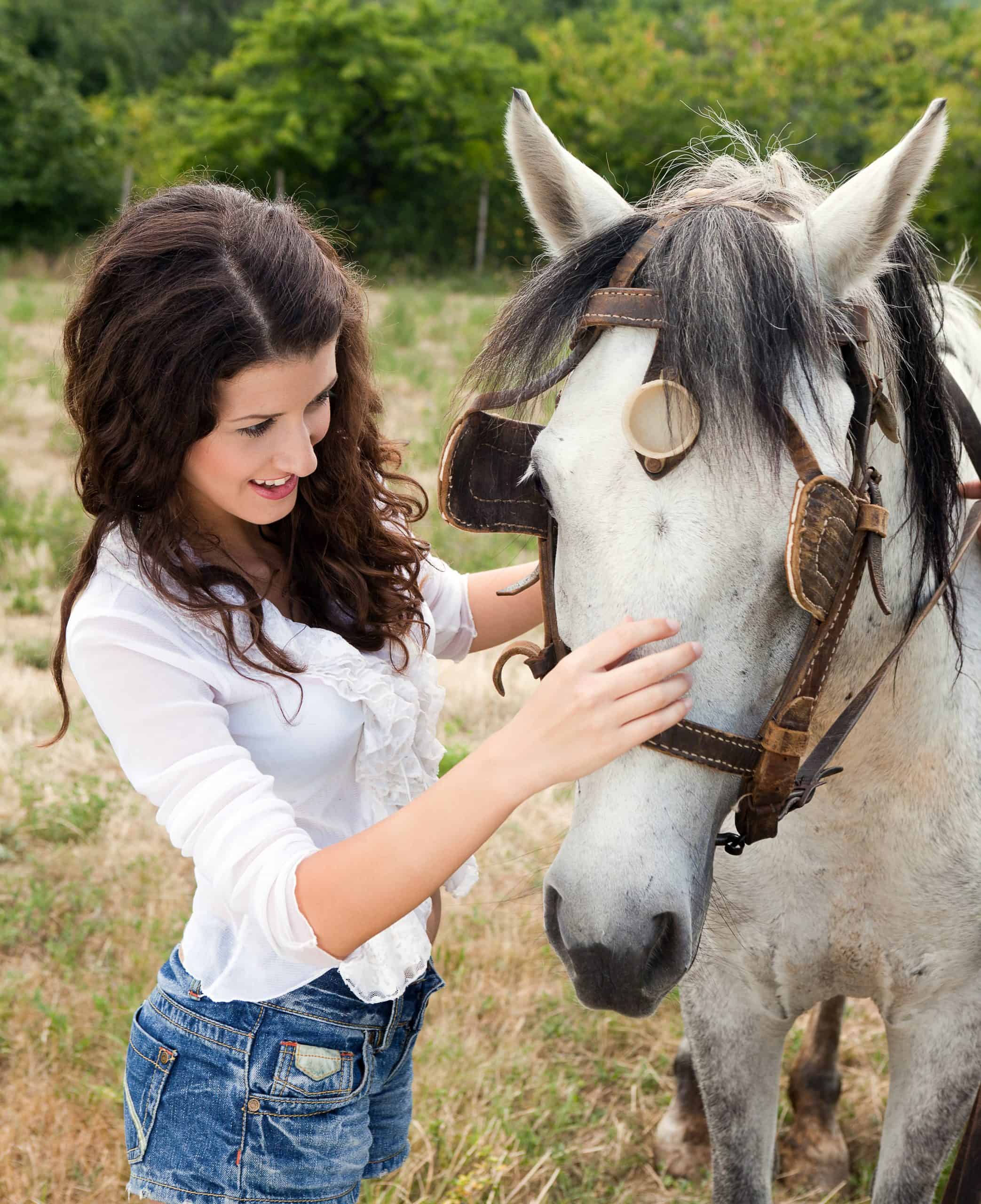 Smiling woman meeting a farm horse in a meadow