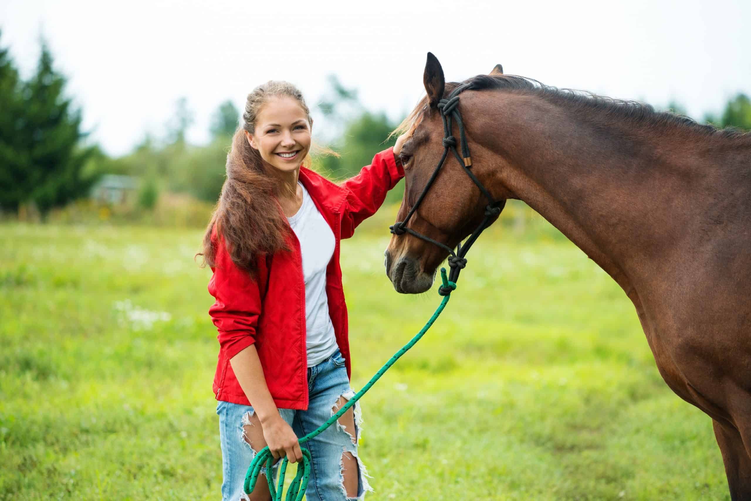 Beautiful smiling girl with her brown horse outdoors