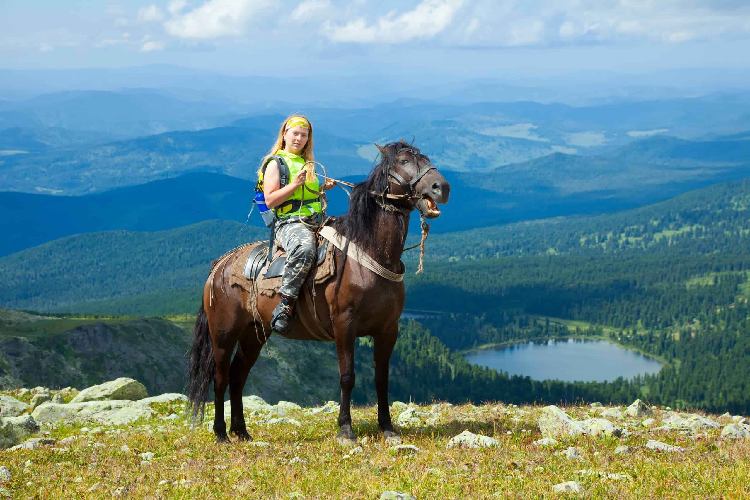 Female rider on horseback at mountains peak. Karakol lakes, Altai