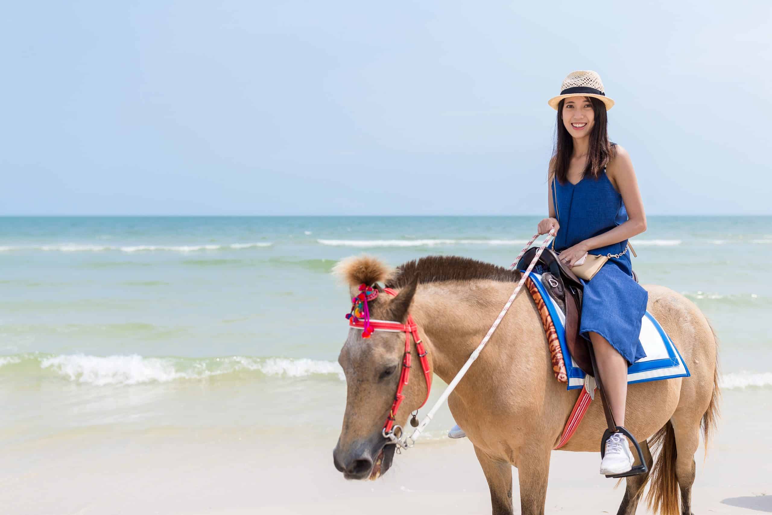 Woman riding horse in the sand beach