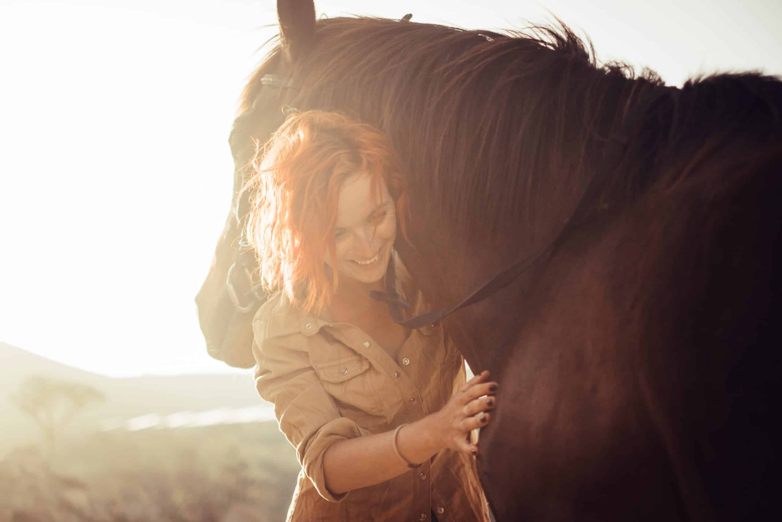real love and friendship concept between nice beautiful caucasian lady and amazing horse. sunset time and backlight. sweetness and tenderness in horses therapy.
