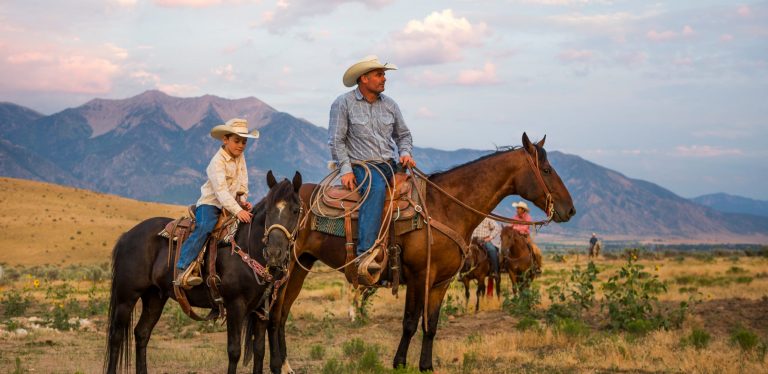 A father and son look over their ranch on horseback