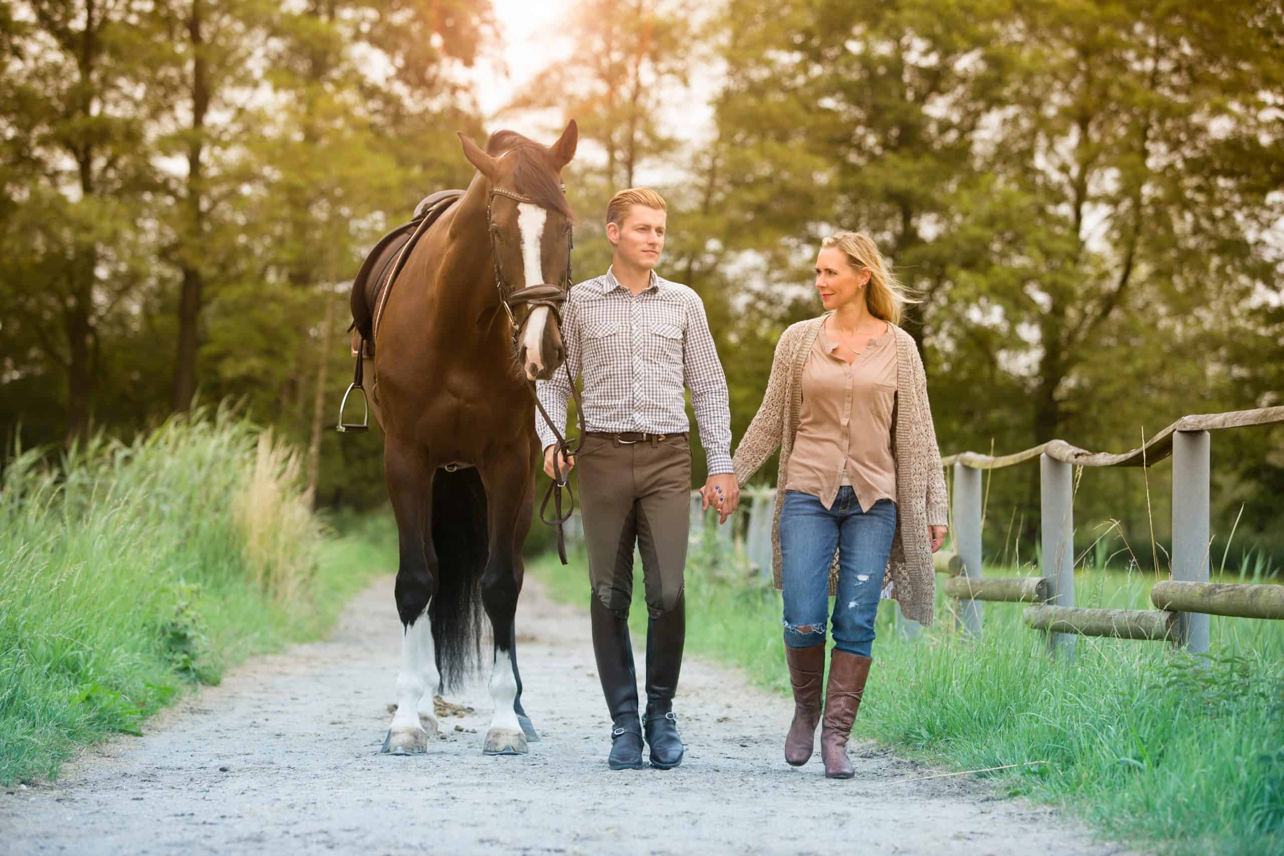man and woman walking with horse on farmland
