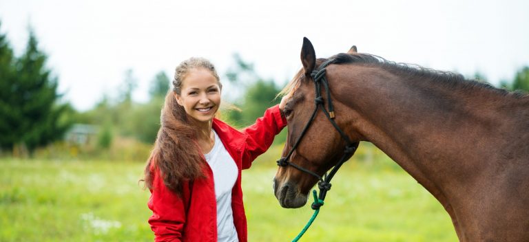 Beautiful smiling girl with her brown horse outdoors