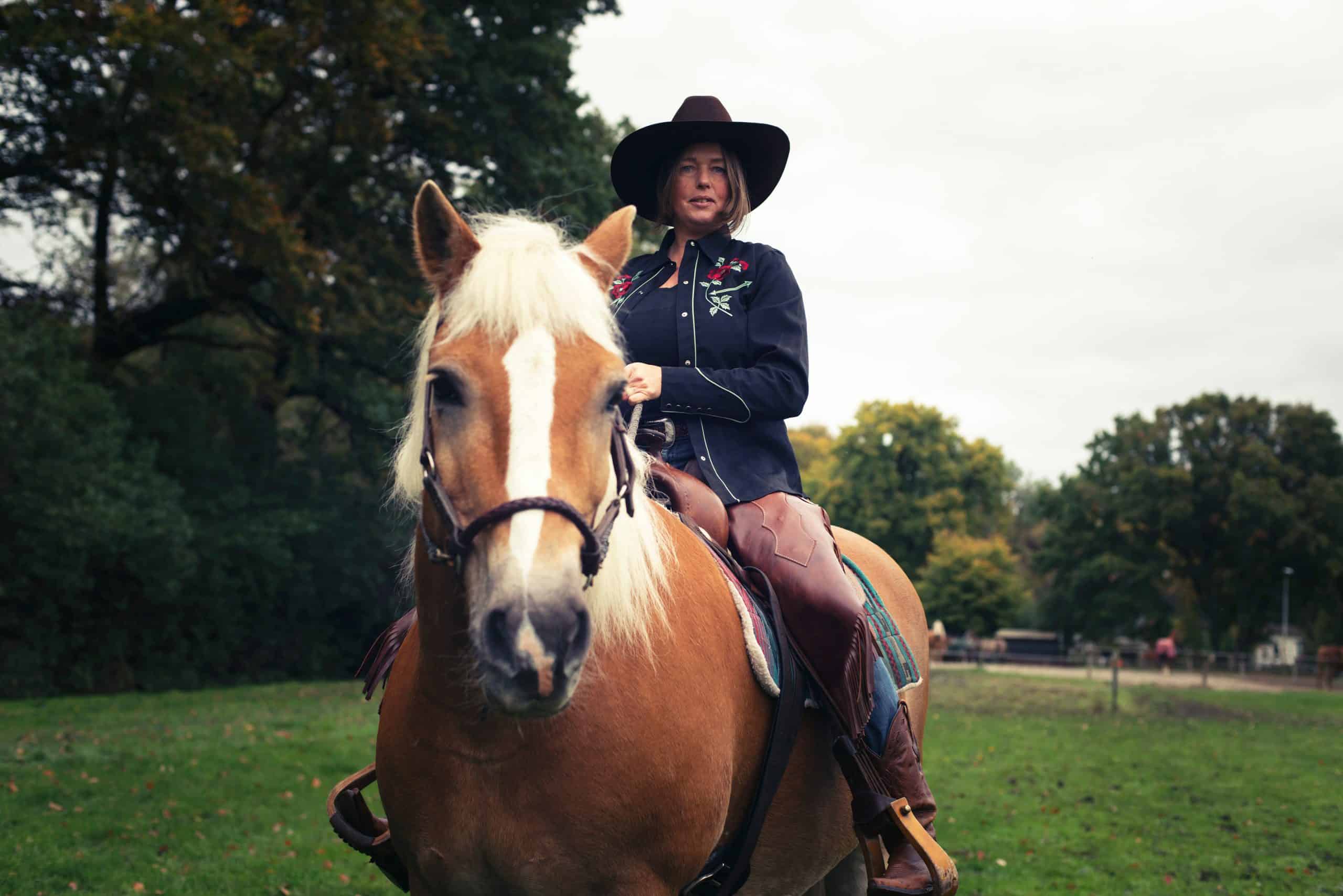 horses mental health benefits Smiling western style woman horse riding in countryside.