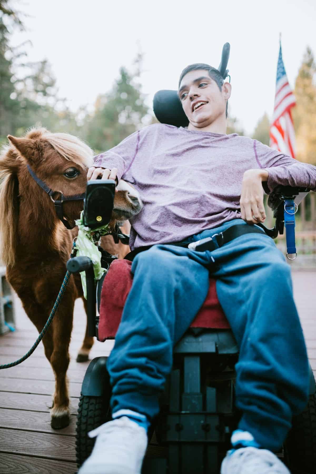 Man in purple shirt in wheelchair by horse