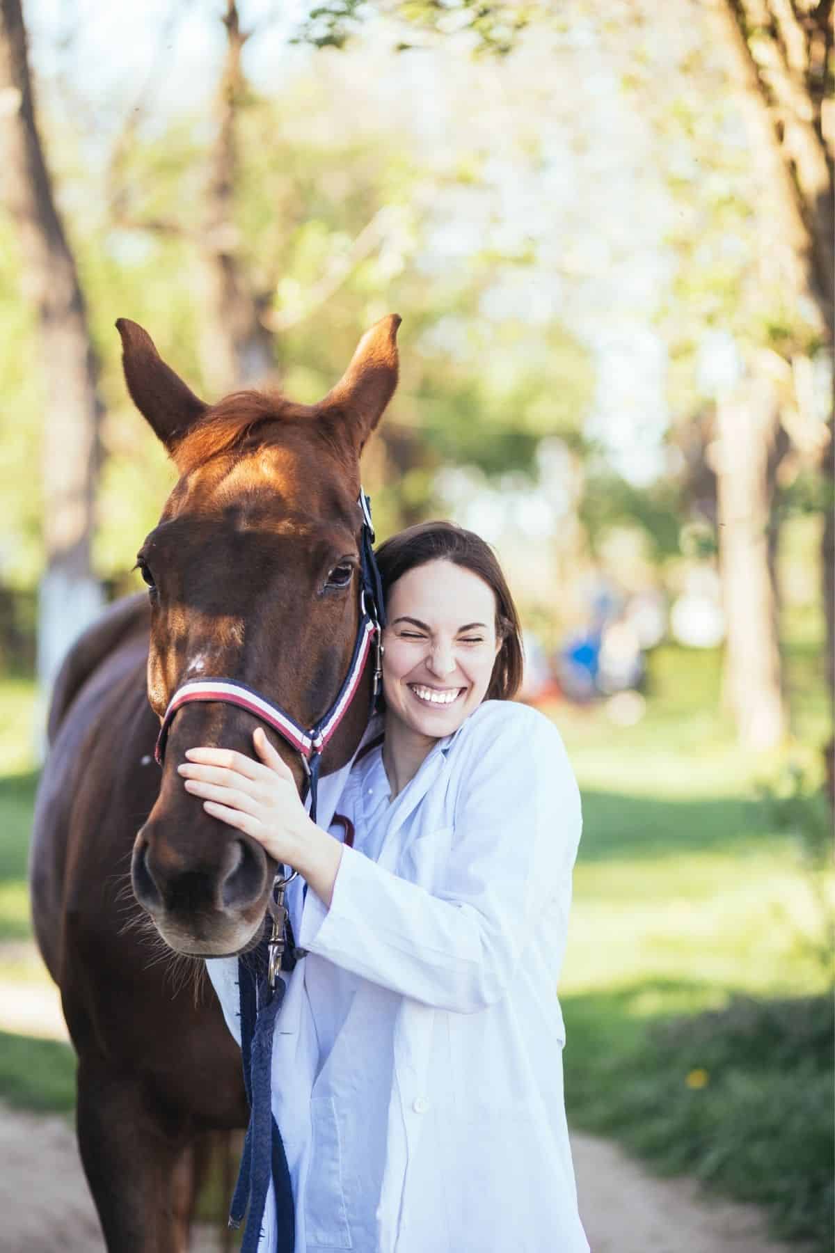 Woman smiling next to brown horse