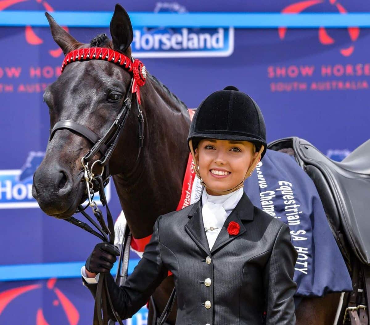 A smiling rider with her brown horse.