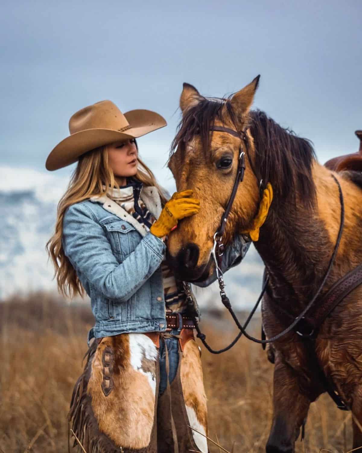 A young woman pets a brown horse.