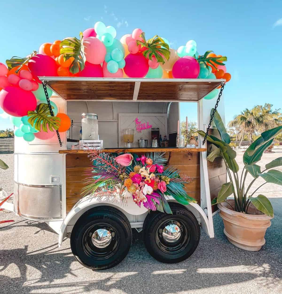 A horse trailer decorated with balloons  rebuilded as a small bar on a beach.
