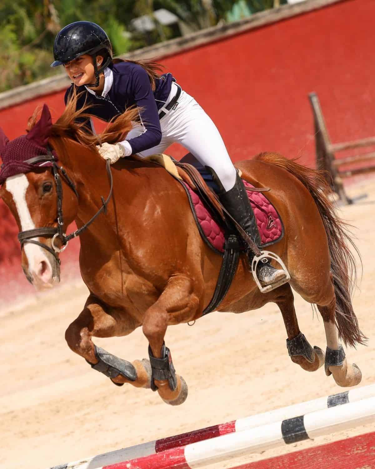 A young woman rides a brown horse.