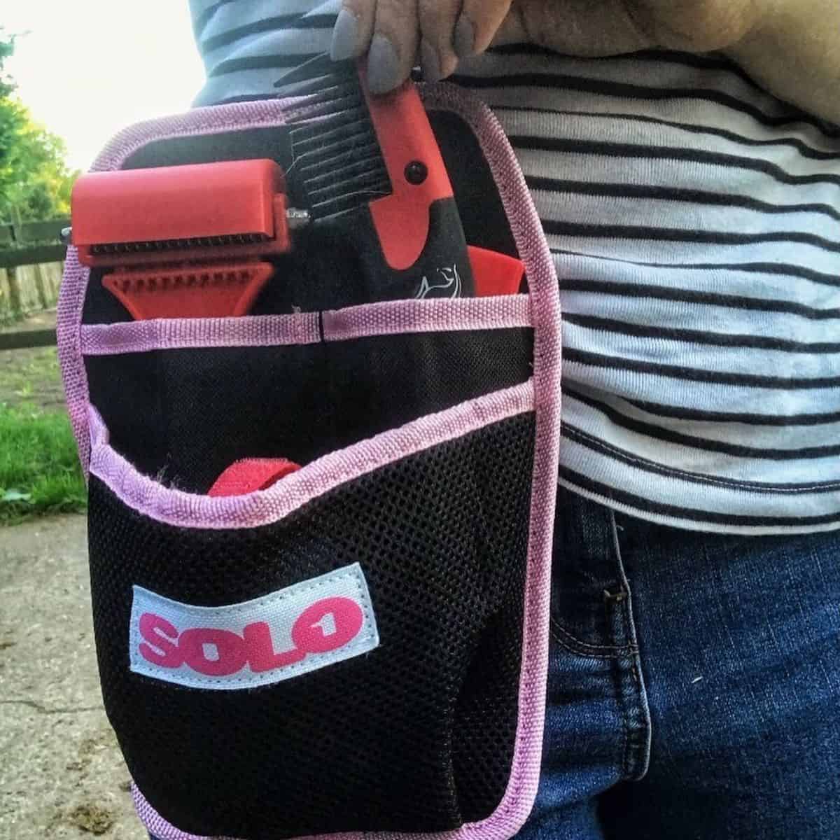 A horse comb and a brush hanging on an owner‘s waist.