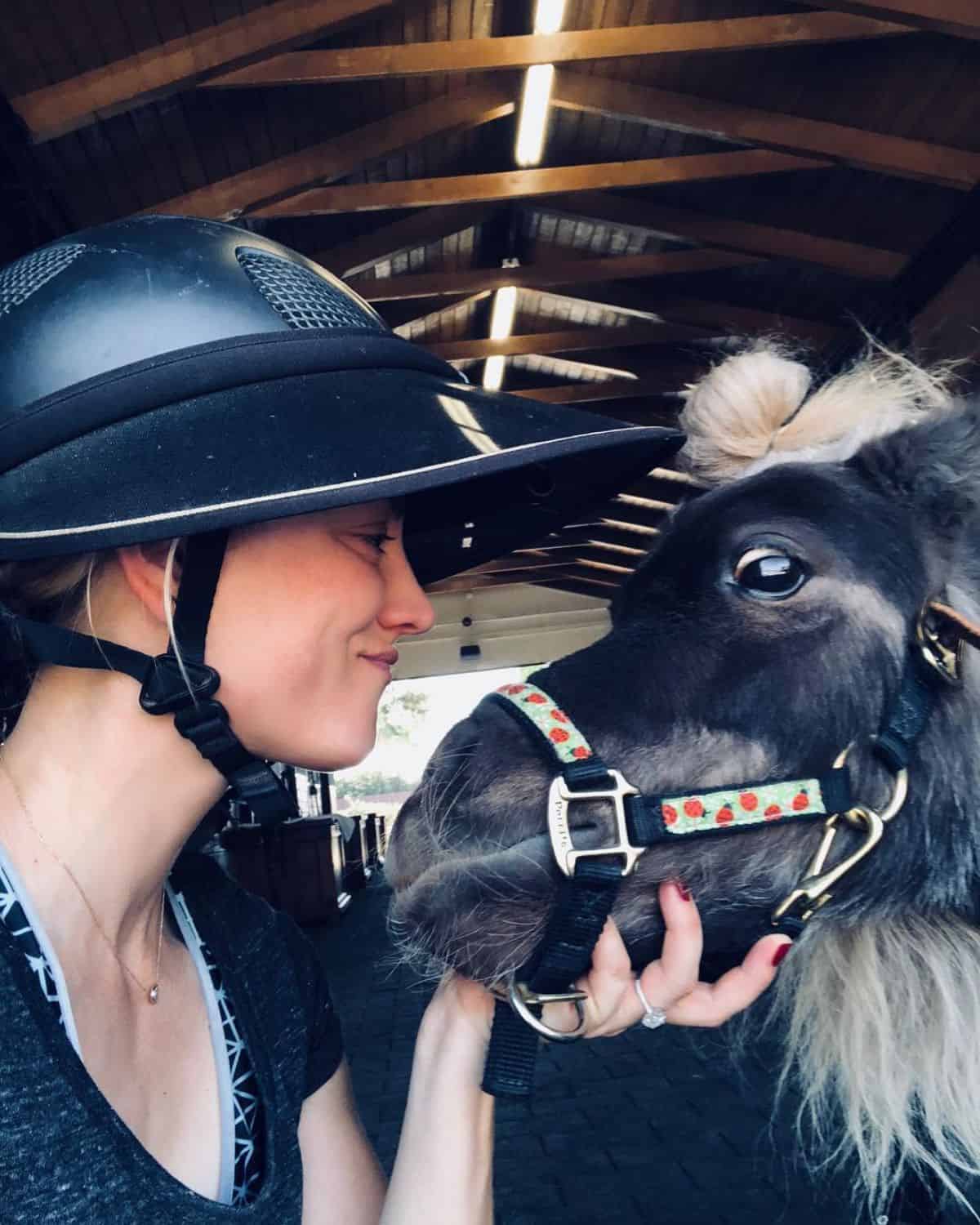 Kaley Cuoco petting her pony.