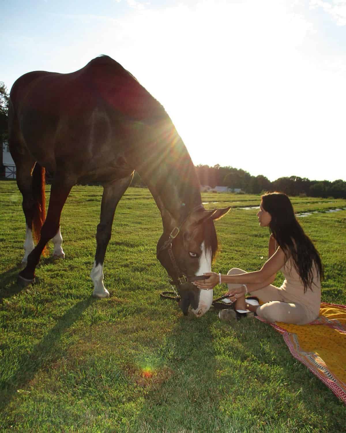 Bella Hadid petting her brown horse.