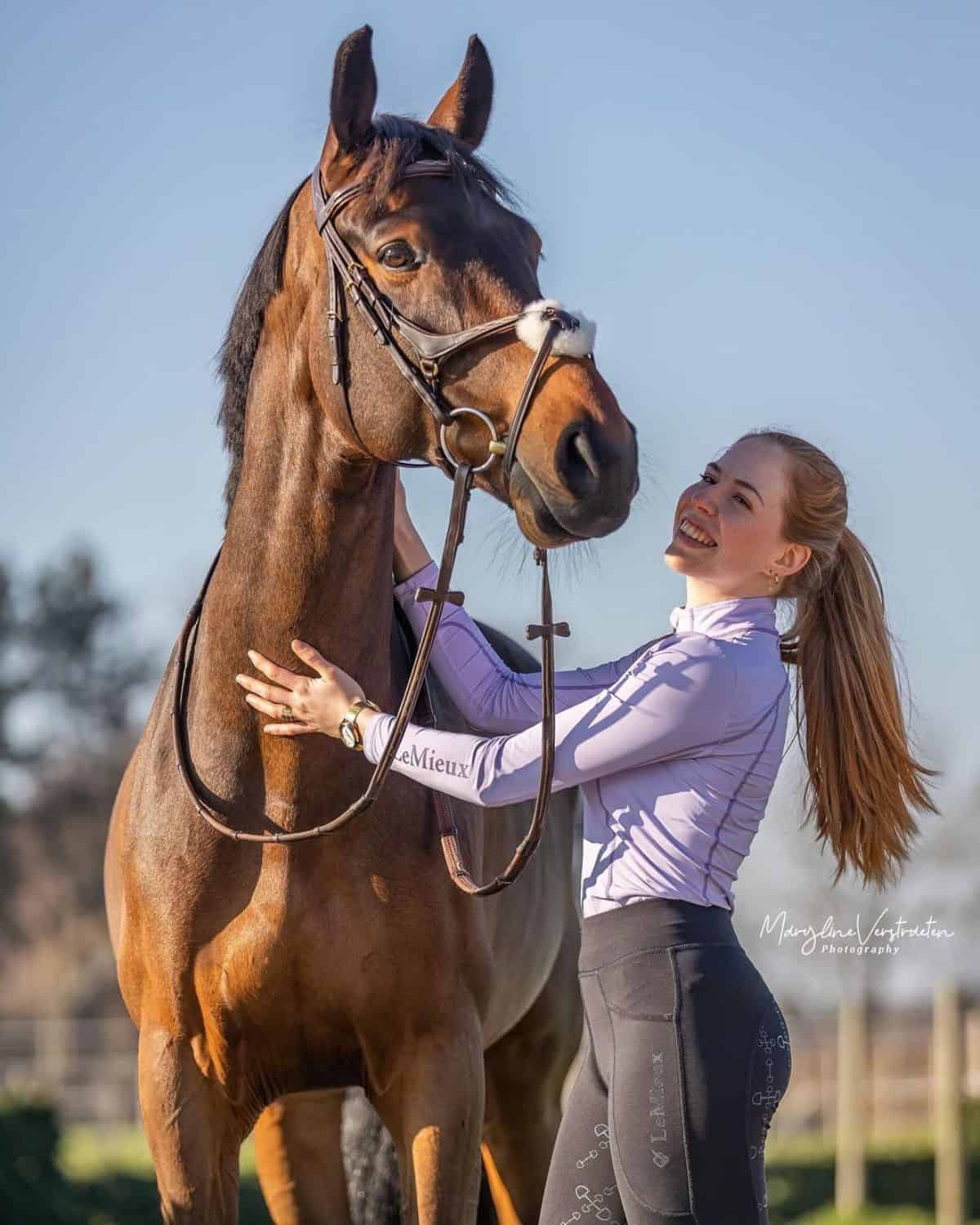 A young woman pets a brown horse.