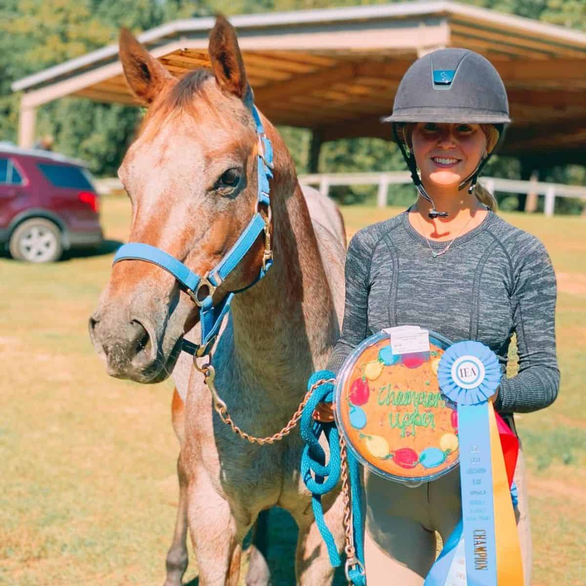 A young woman with a medal stands near a Pony of the Americas.