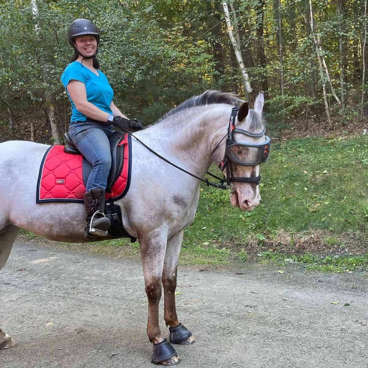 A woman riding a gray Colorado Ranger horse.