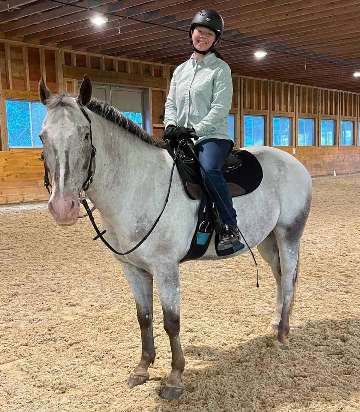 A woman riding a gray Colorado Ranger horse.
