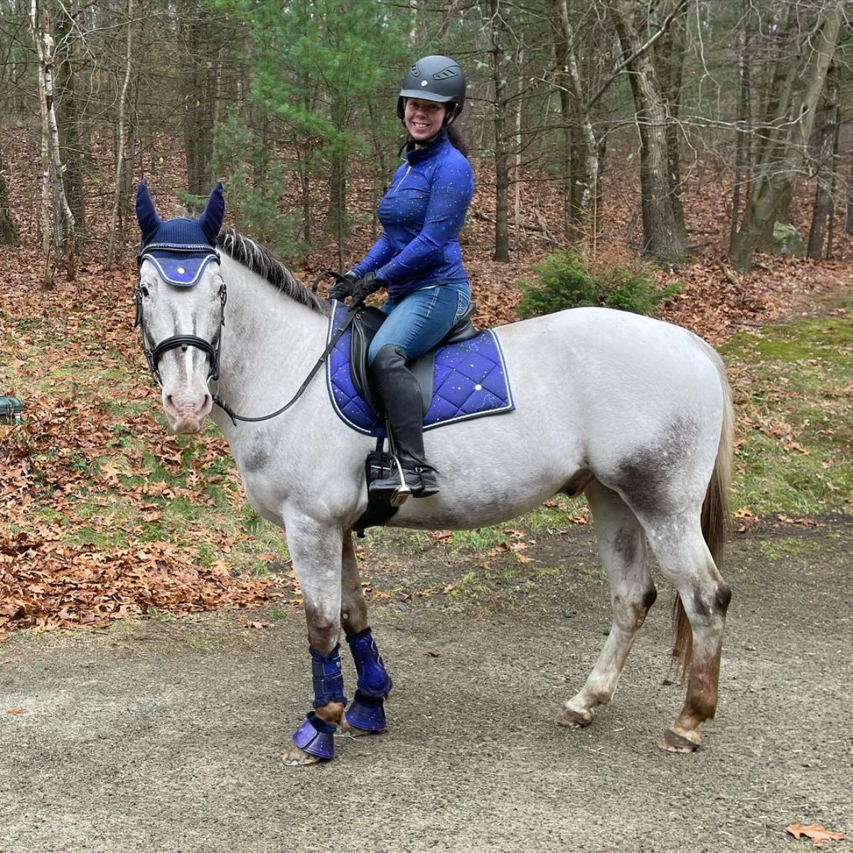 A young woman riding a gray Colorado Ranger horse.