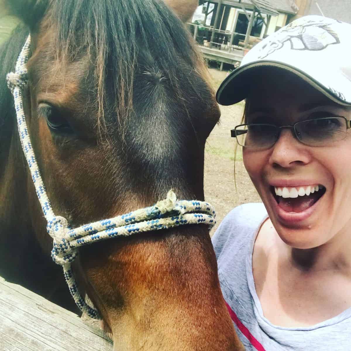 A woman and a brown horse selfie.
