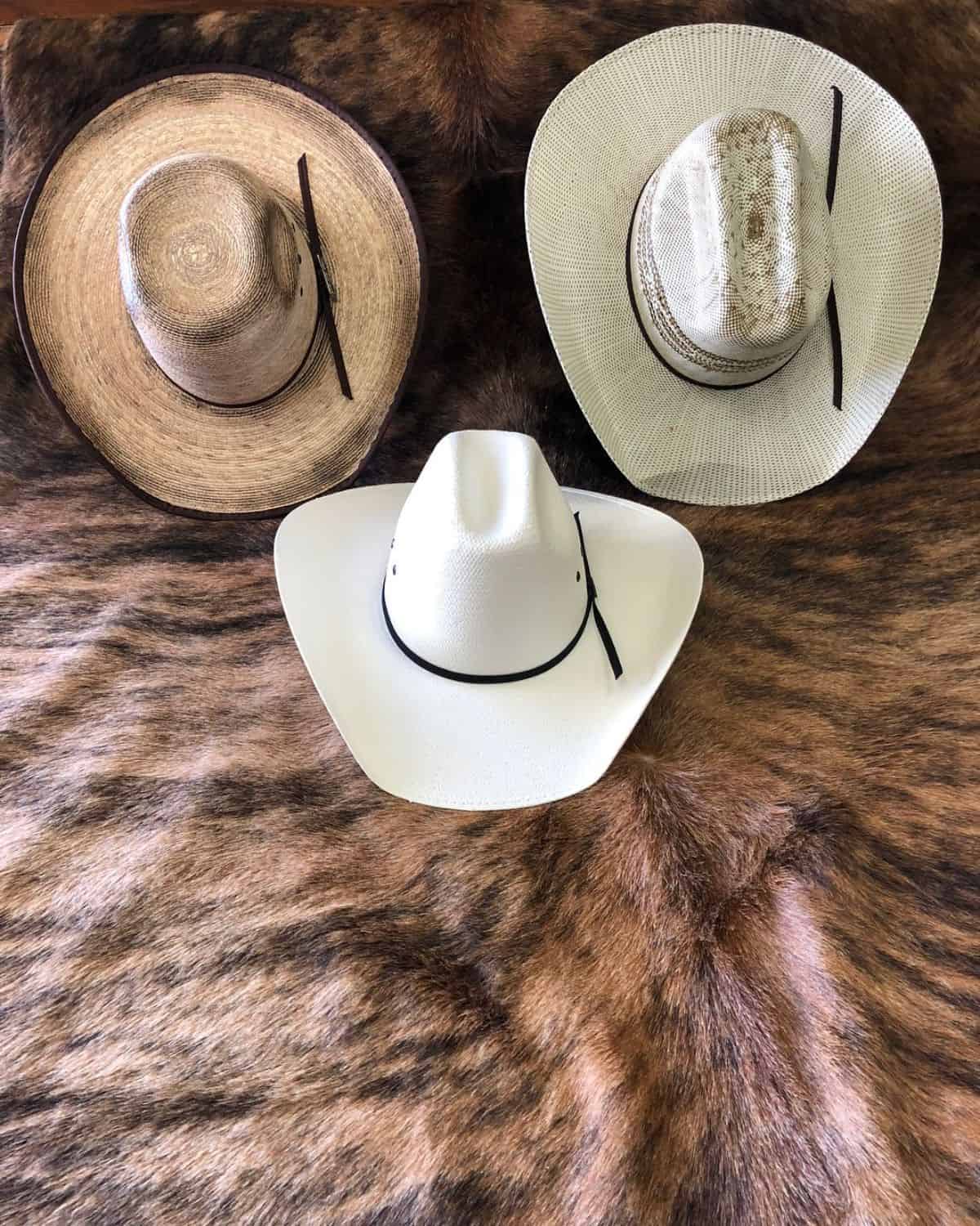 Three cowboy hats on a blanket.