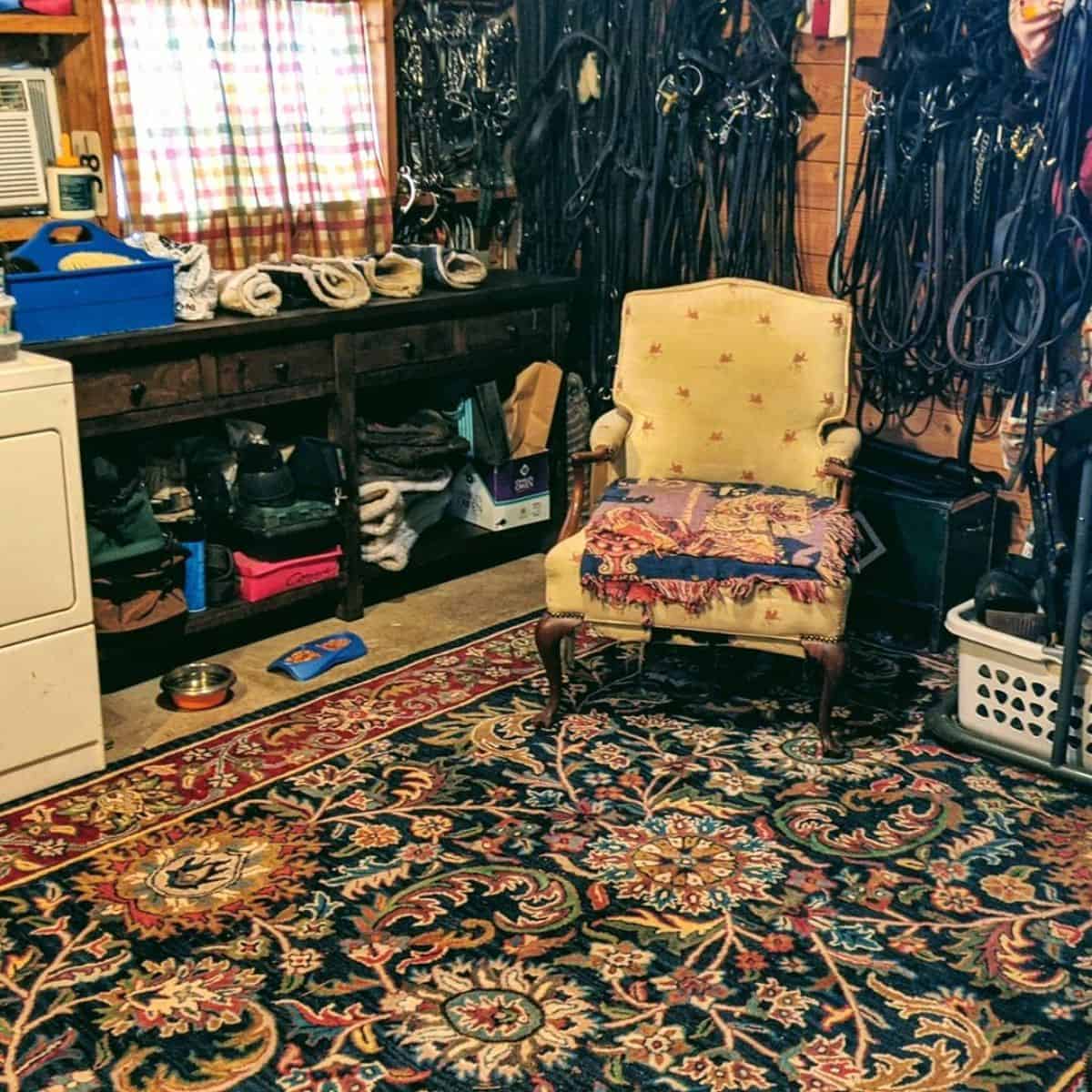 A tack room filled with horse accessories and a cozy armchair.