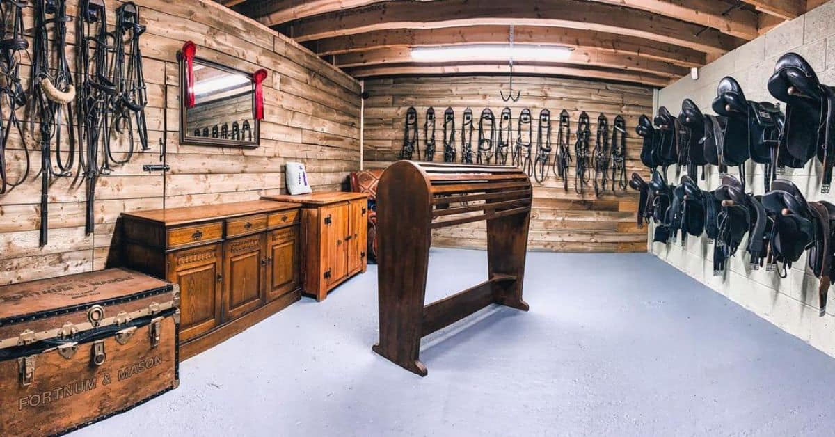A rustic tack room filled with horse accessories hanging on the walls.