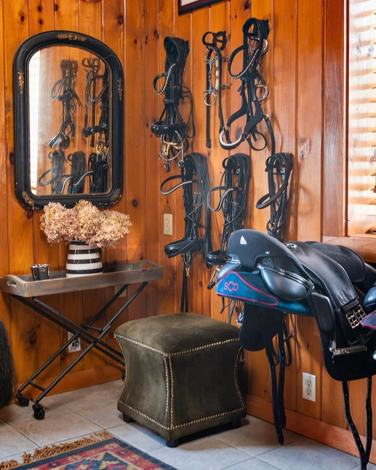 A rustic tack room with horse accessories hanging on a wall.