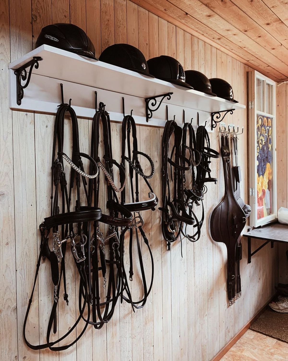 A tack room filled with horse riding accessories on a wall.