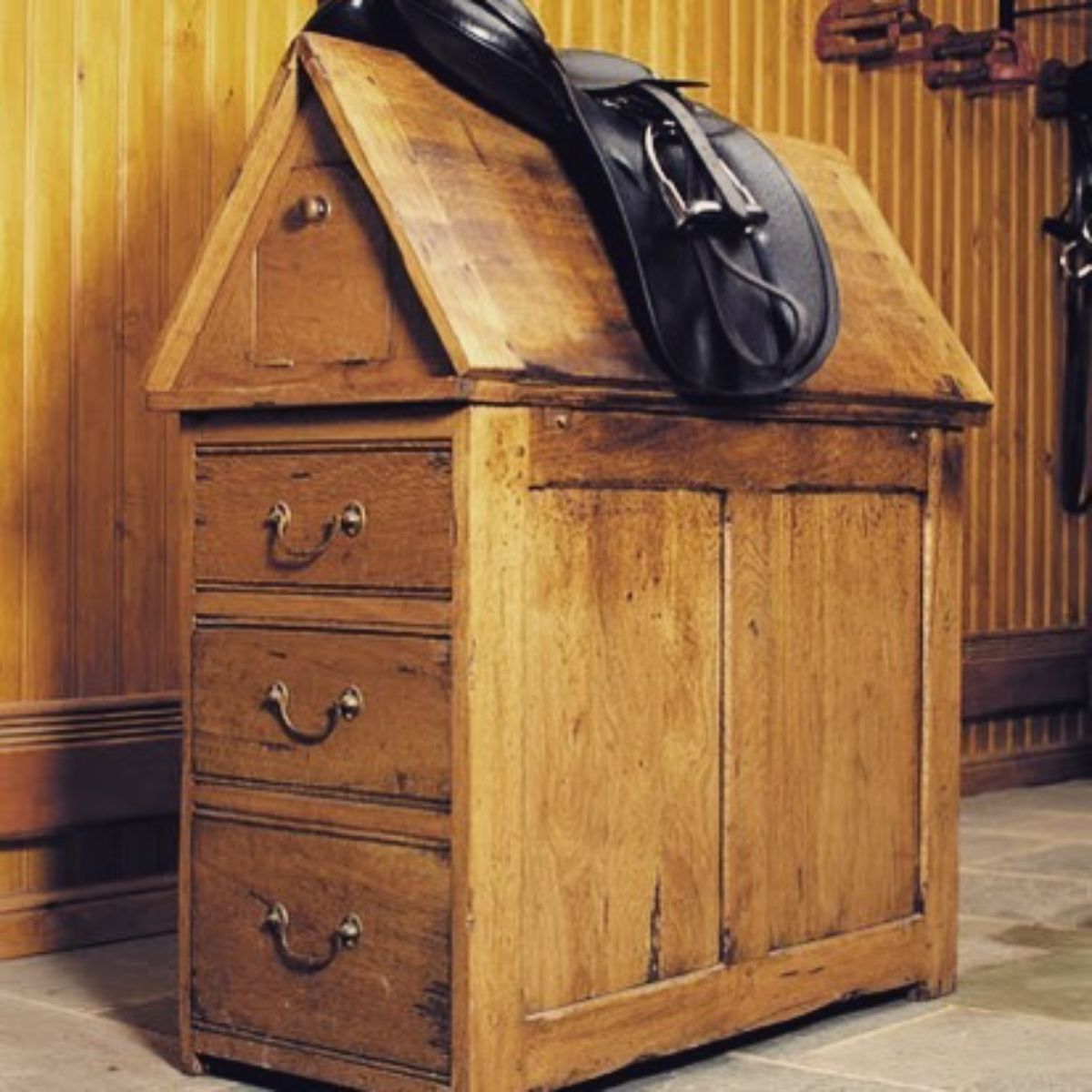 A wooden rustic saddle rack with a leather saddle on the top.