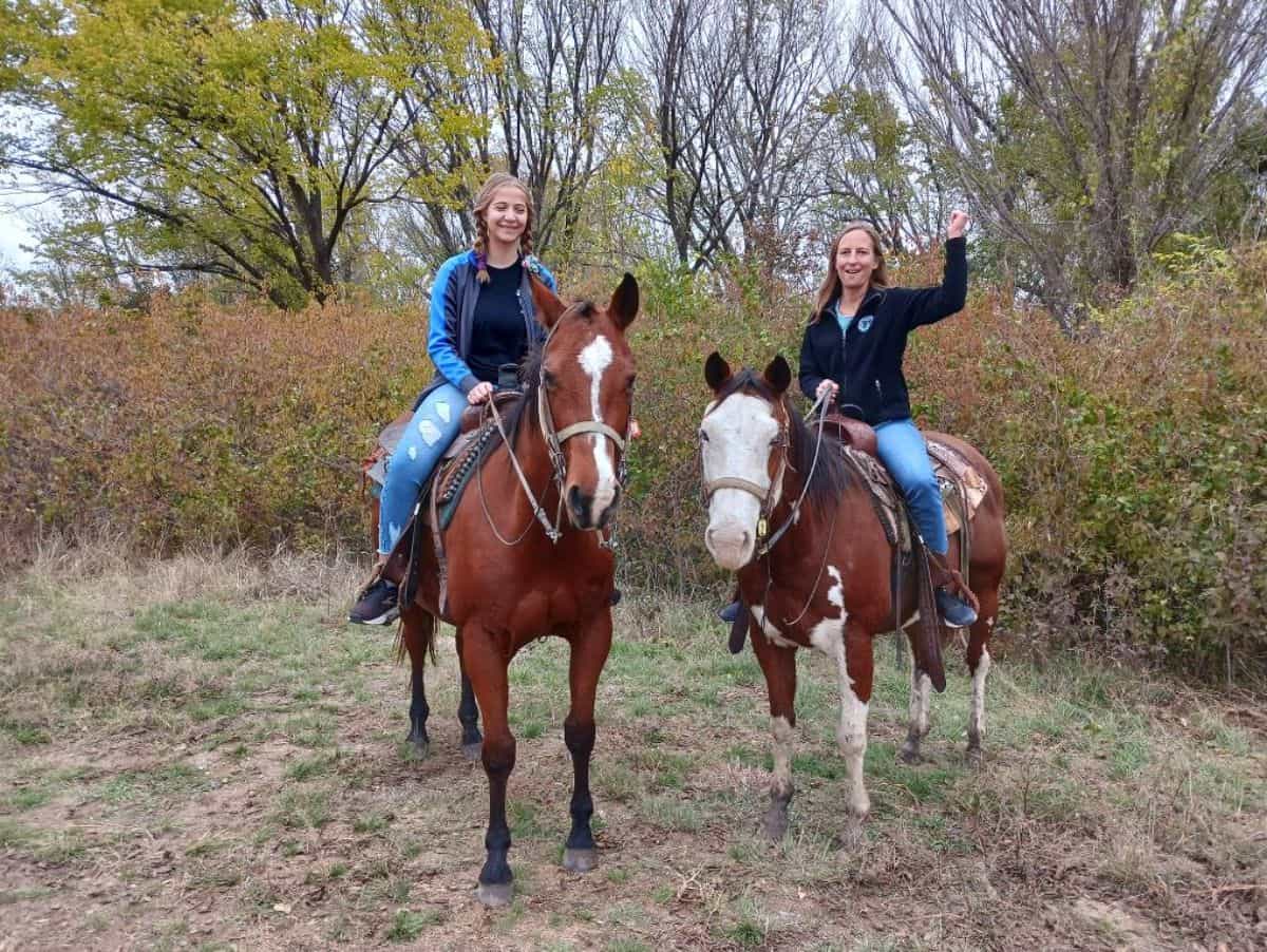 Two young women enjoying a horseback ride.