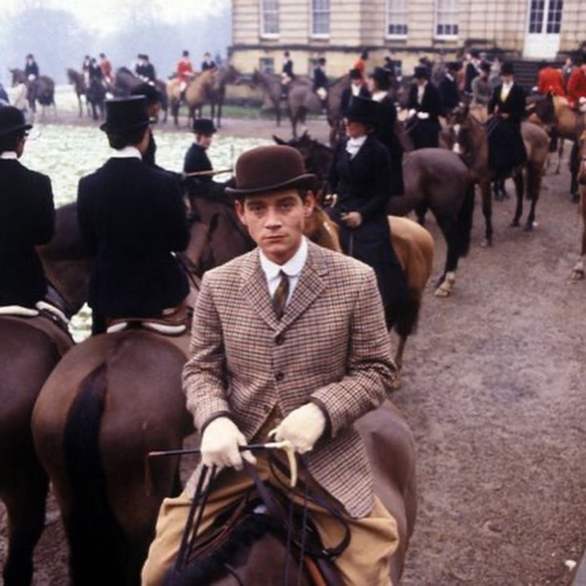 A man in classic Equestrian outfit rides a horse.