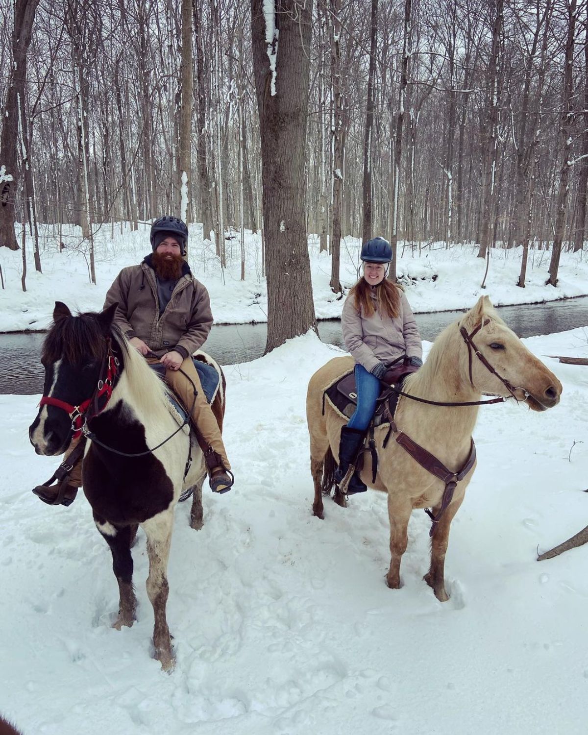 A young couple enjoys a horse ride during the winter.