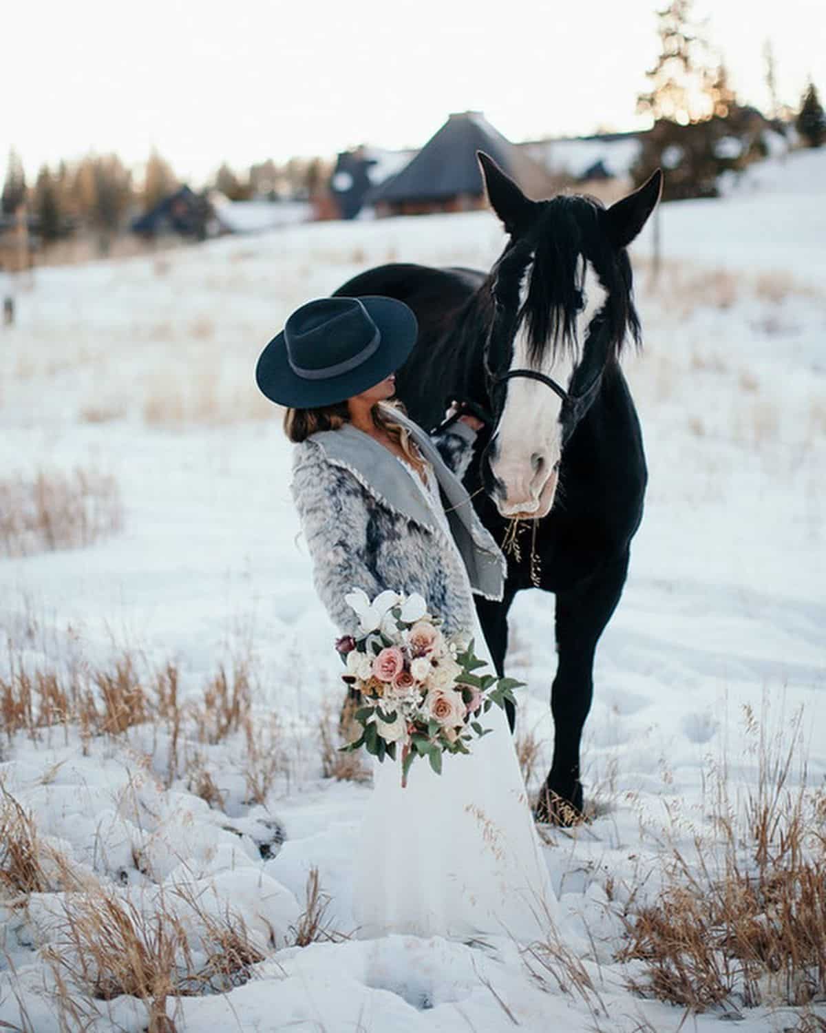 A woman with flower pets a brown horse.