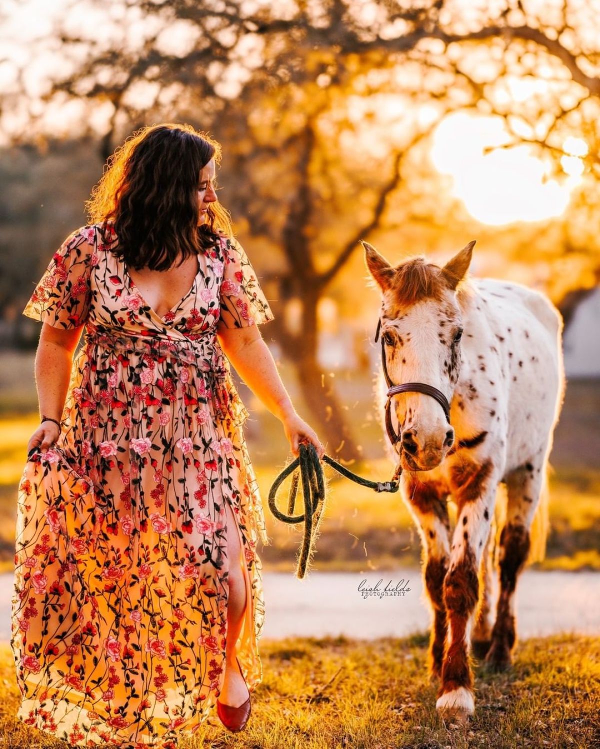 A woman in a colorful dress leads a Pony of the Americas.