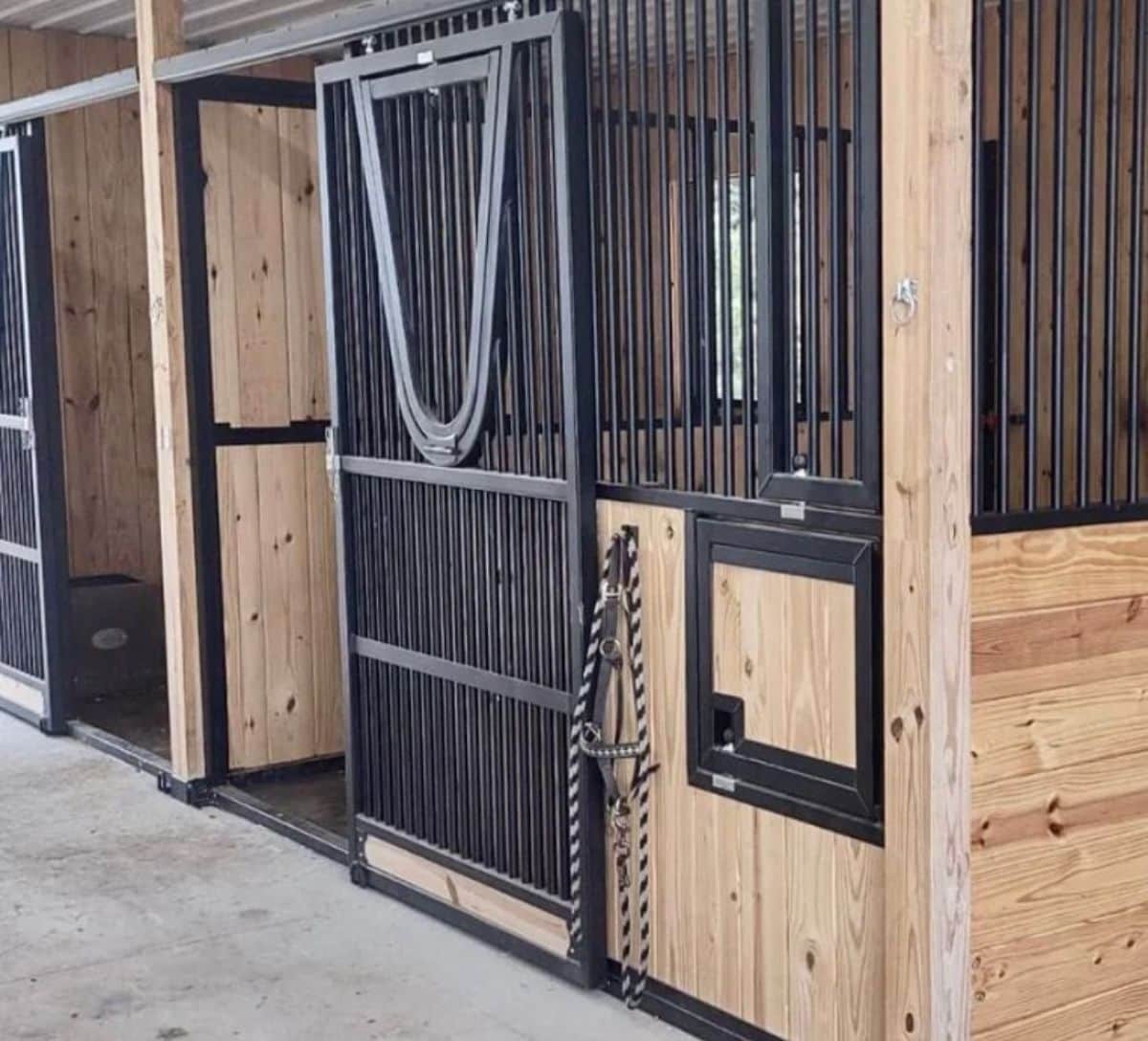 A wooden horse stall with a metal gate.